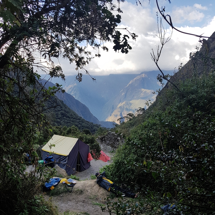 Tentes de camping installées dans une région montagneuse avec des nuages.
