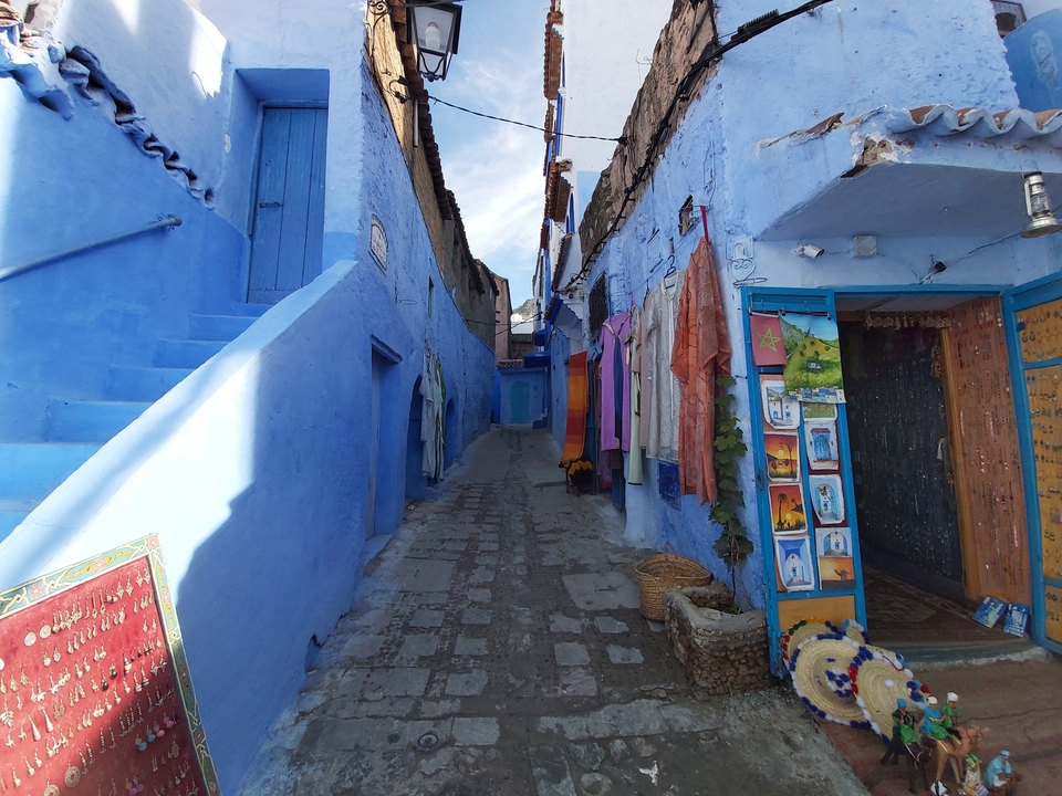 Rue peinte en bleu avec des textiles colorés en exposition.