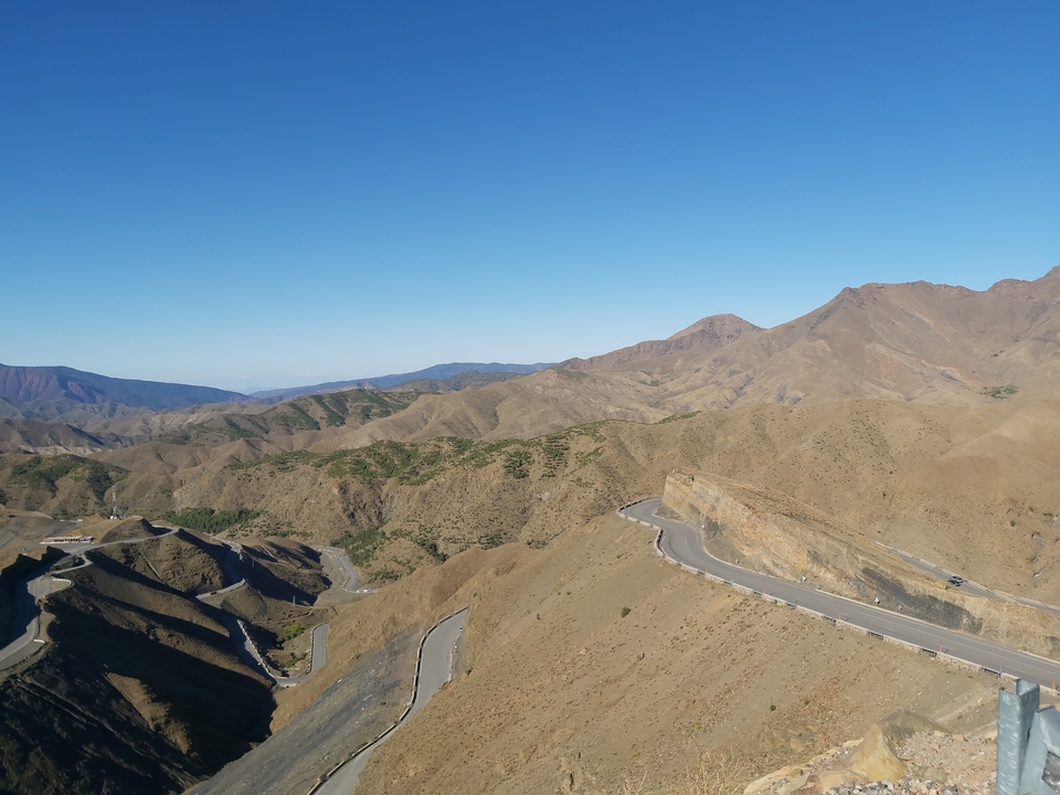 Route sinueuse à travers des montagnes arides sous un ciel bleu dégagé.