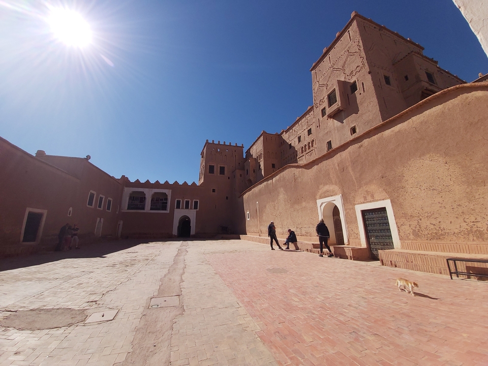 Cour avec bâtiments traditionnels et personnes qui interagissent.