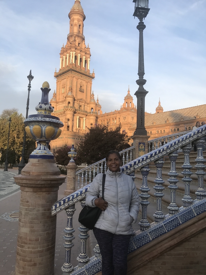 Femme posant devant un bâtiment historique aux carreaux détaillés.