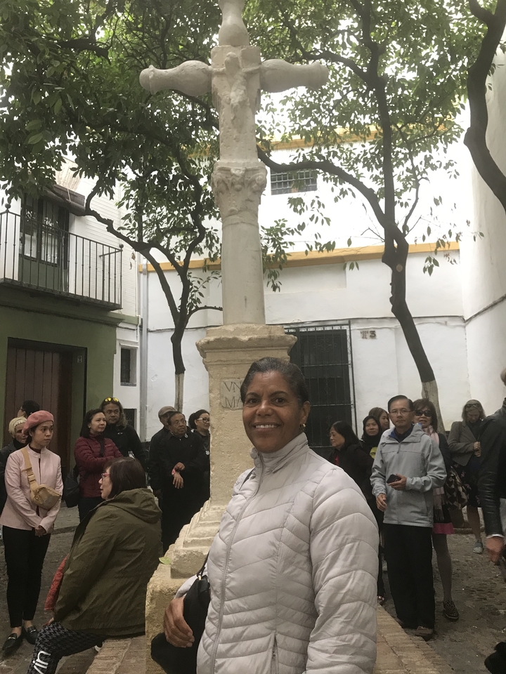 Femme debout au milieu d'un groupe de touristes avec une colonne historique.