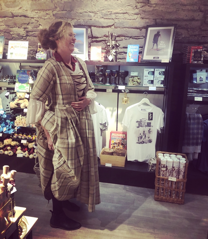 Un mannequin en vêtements traditionnels dans un magasin avec divers articles à vendre.