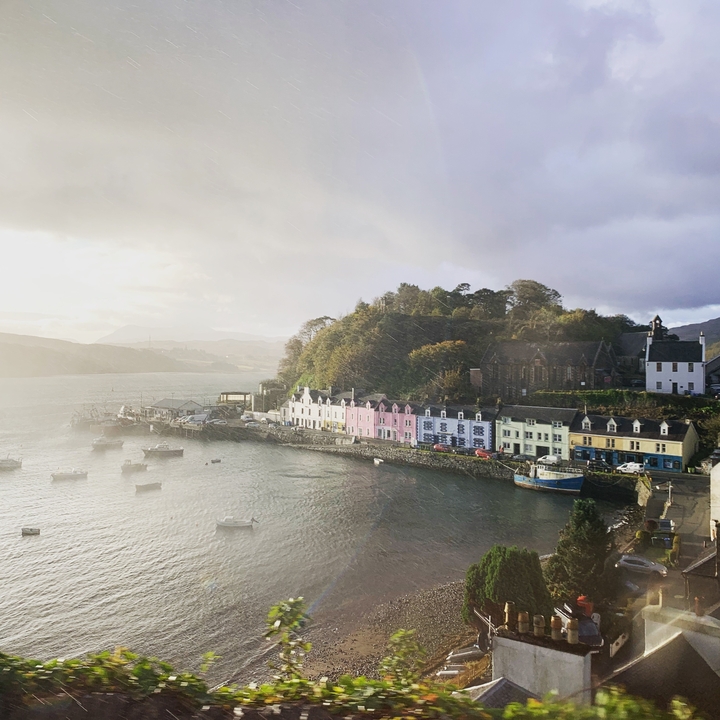 Vue de bâtiments colorés au bord de l'eau avec des bateaux et une falaise en arrière-plan.