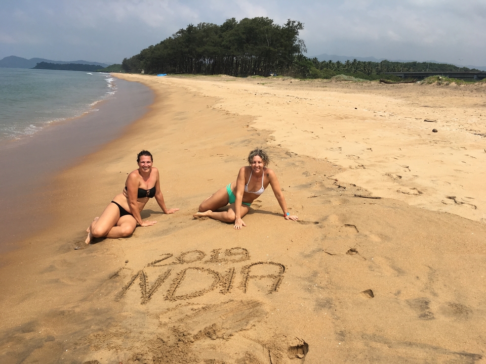 Deux personnes sur une plage avec « 2019 INDIA » écrit dans le sable.