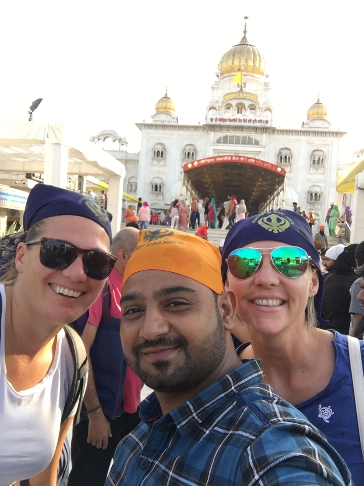 Trois amies avec des foulards devant l'entrée d'un temple.