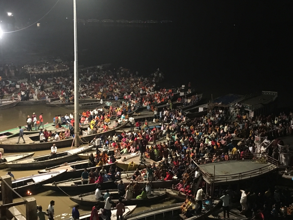Grand nombre de personnes sur des bateaux la nuit sur une rivière.