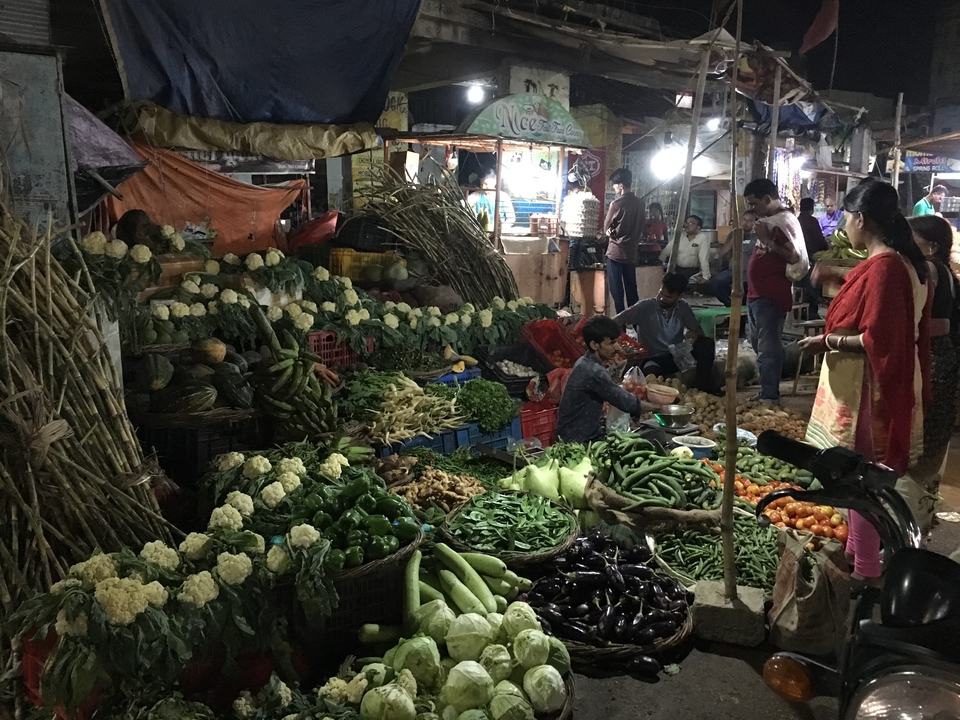 Marché nocturne avec divers légumes et des gens qui font leurs courses.