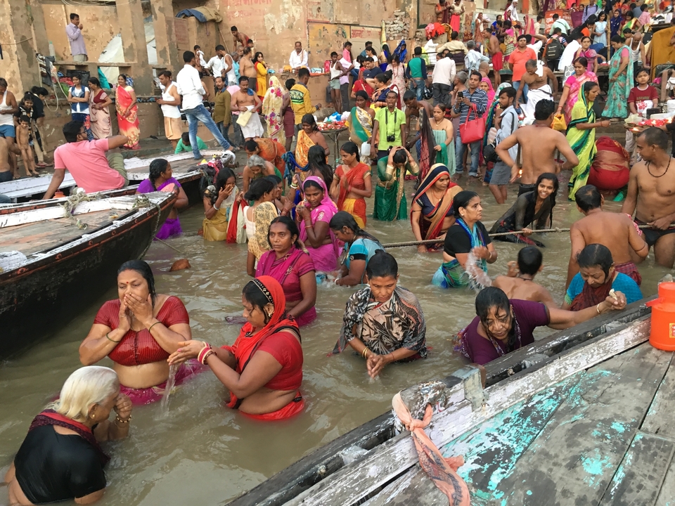 Un groupe de personnes participant à un bain rituel au bord d'une rivière.