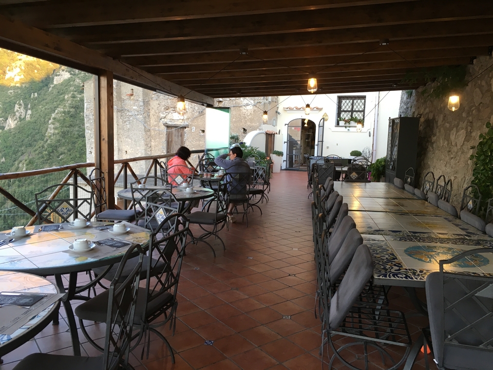 Terrasse extérieure avec tables et murs en pierre.