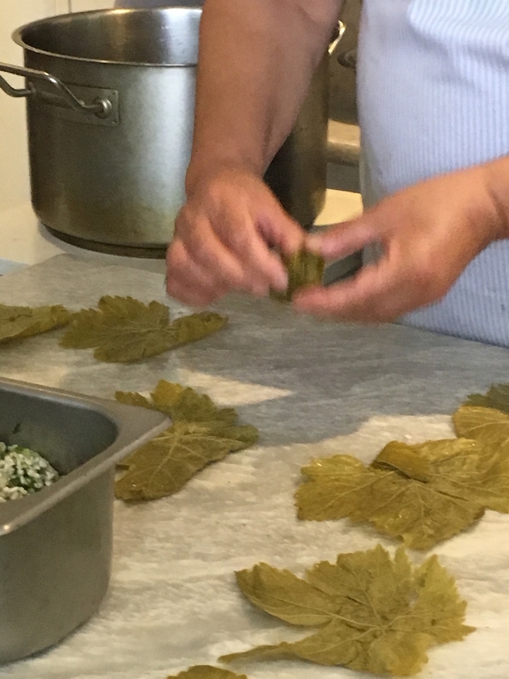 Mains préparant des dolmas avec des feuilles de vigne.