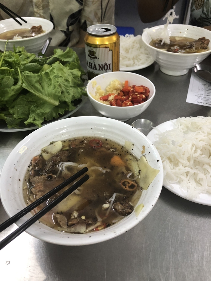 Bol de soupe vietnamienne avec des nouilles et divers ingrédients.