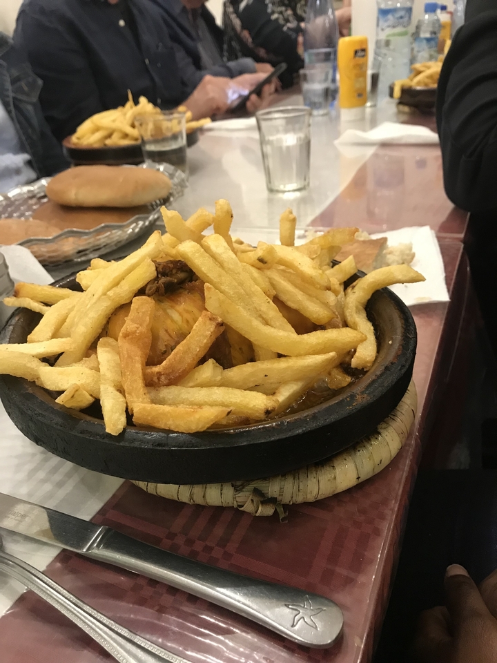 Tajine de poulet avec des frites dessus.