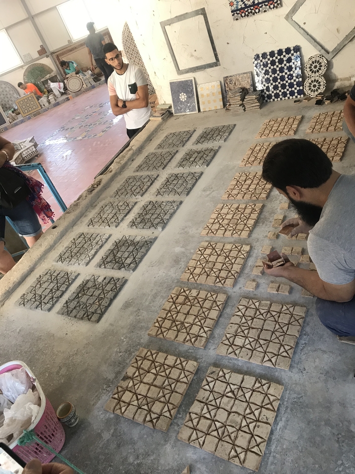 Des personnes observant le processus de fabrication de carreaux dans un atelier.