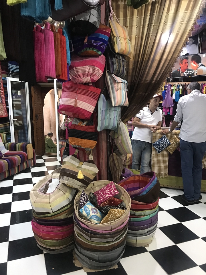 Intérieur de magasin avec des sacs colorés et des gens.