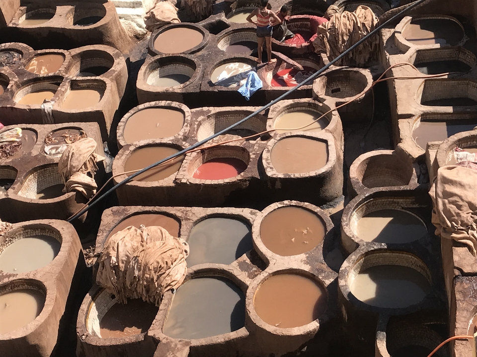 Tannerie traditionnelle marocaine avec des bassins de teinture colorés.