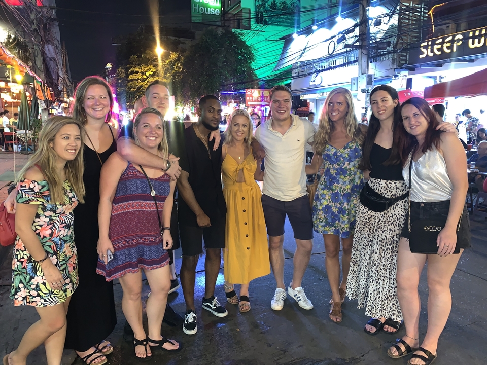 Photo de groupe de personnes dans une rue animée la nuit.