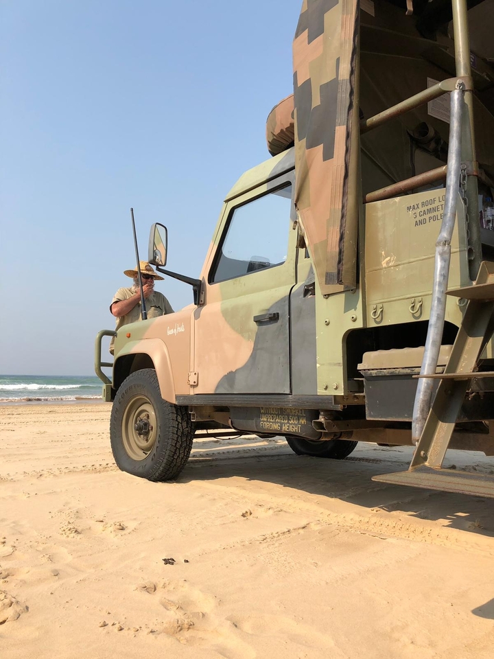 Une personne debout à côté d'un véhicule tout-terrain sur la plage.