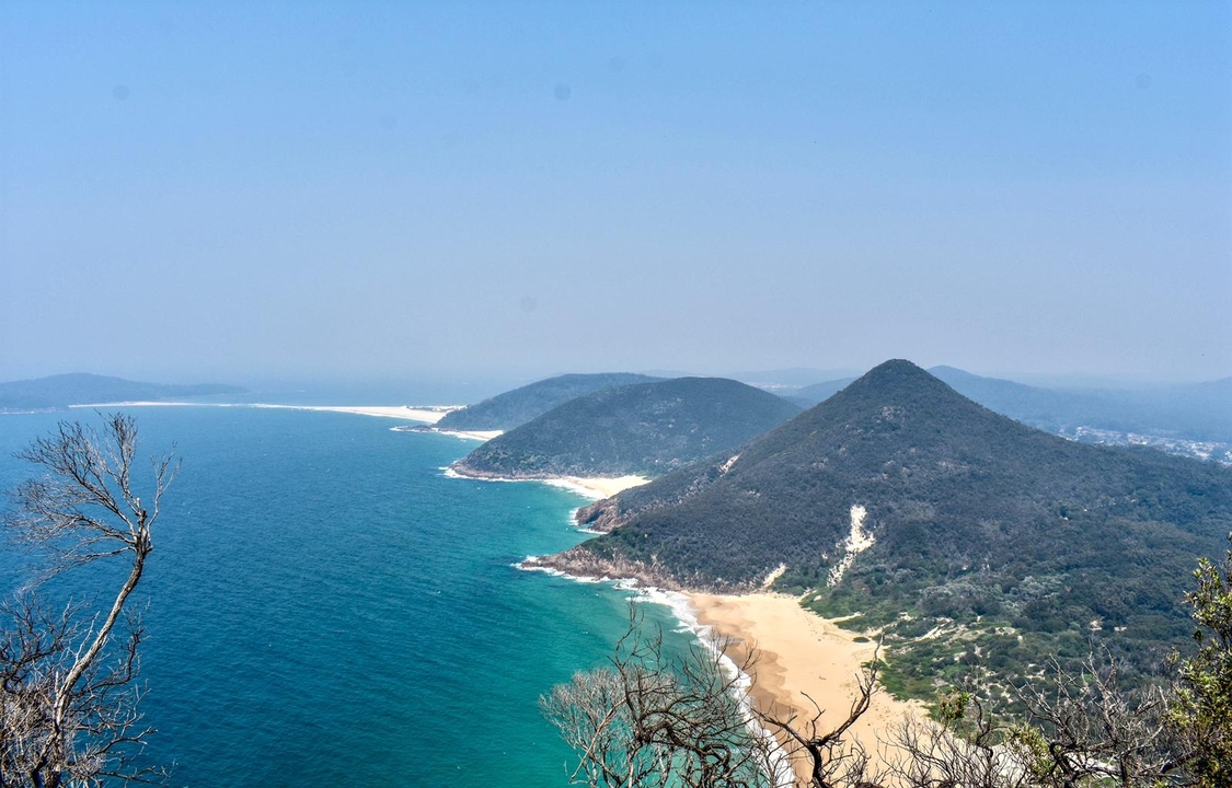 Vue aérienne d'un paysage côtier avec plage de sable et promontoire.