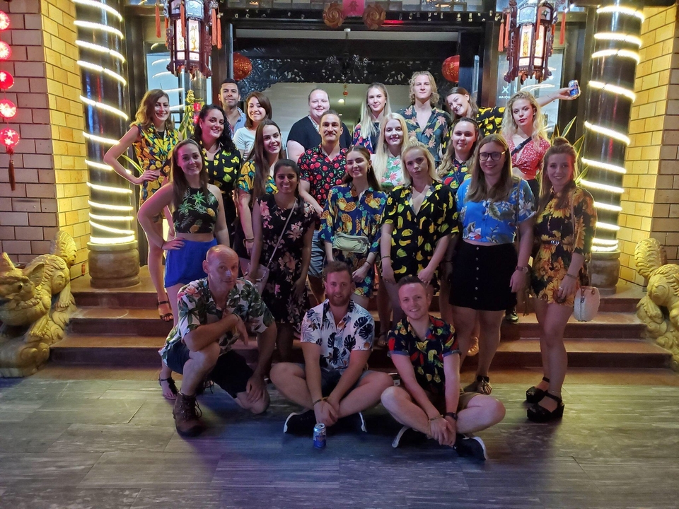 Grand groupe de personnes posant la nuit devant un bâtiment avec des néons.