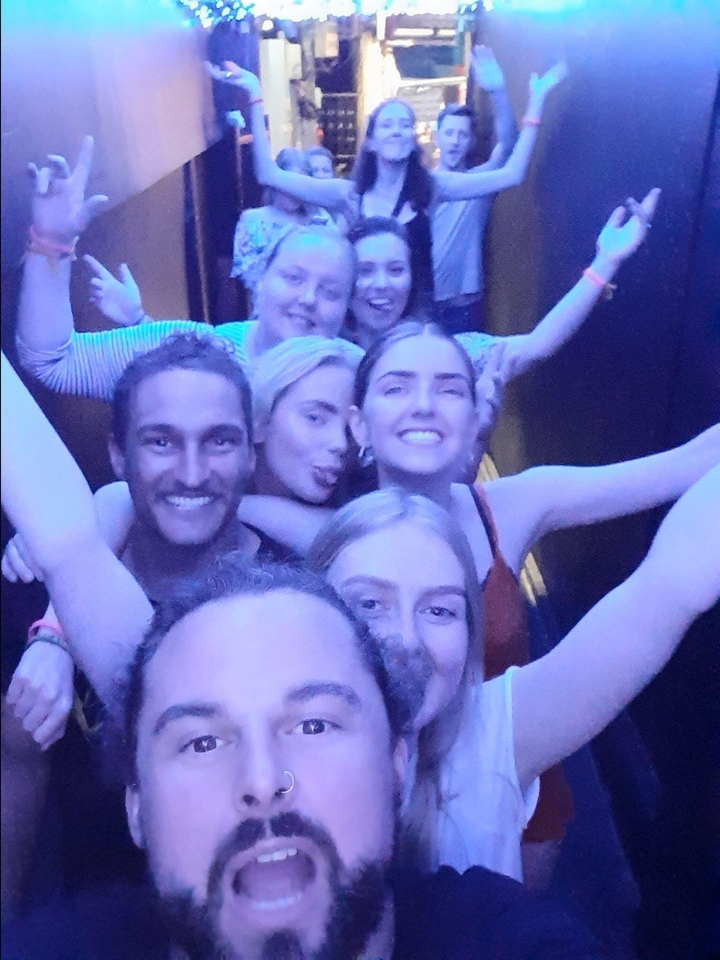 Selfie de groupe avec des personnes qui rient et posent serrées les unes contre les autres à l'intérieur.