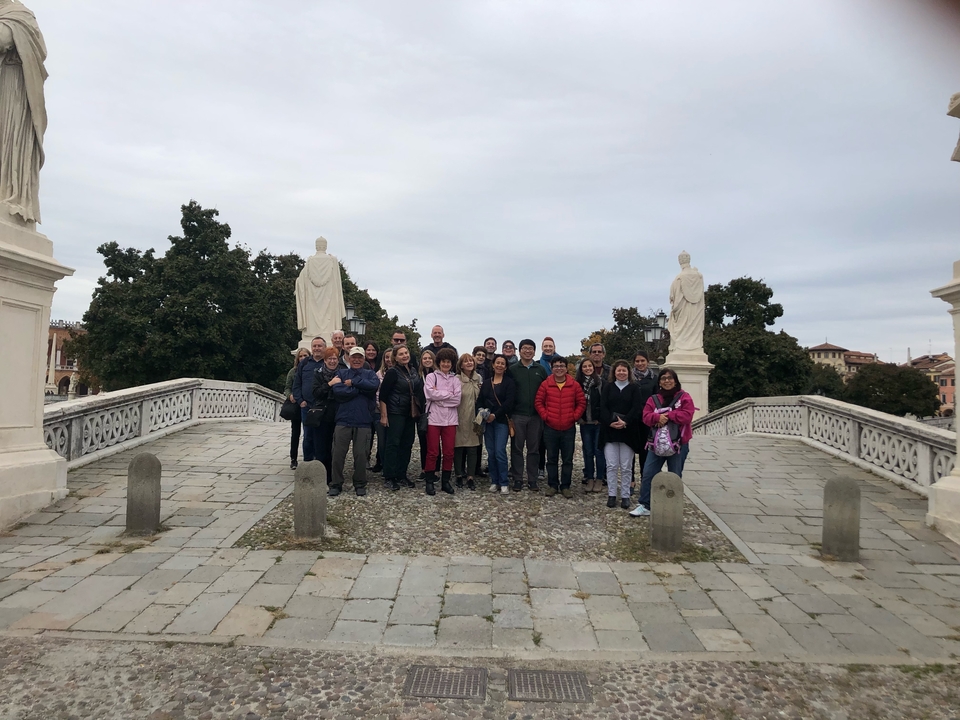 Grand groupe posant sur un pont avec des statues et des arbres en arrière-plan.