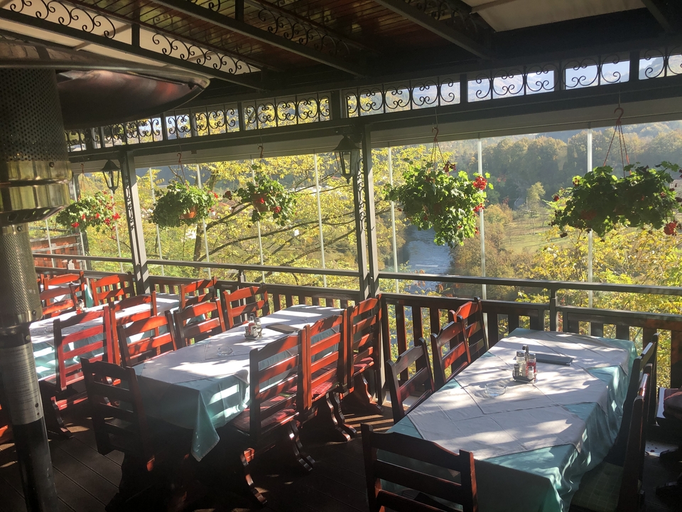 Espace de restauration en plein air avec tables et chaises donnant sur une rivière.