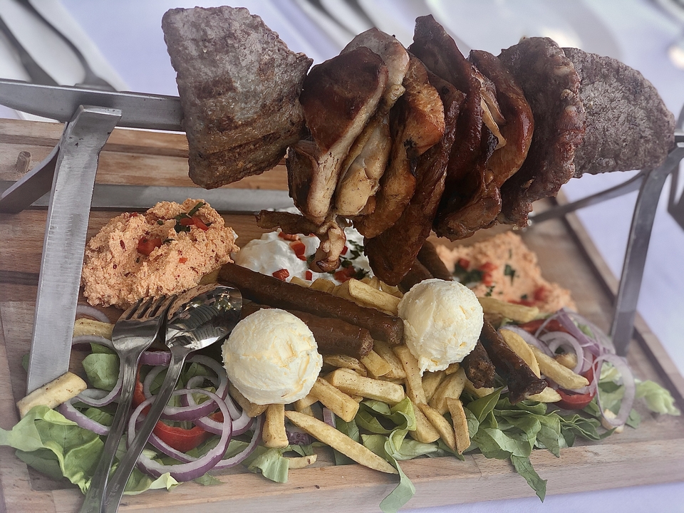 Plateau de barbecue avec viandes assorties et accompagnements.