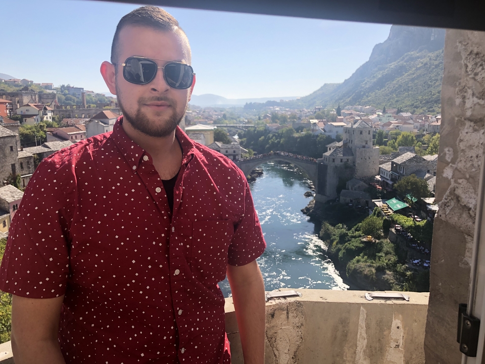 Personne portant des lunettes de soleil avec une rivière et un pont en arc en arrière-plan.