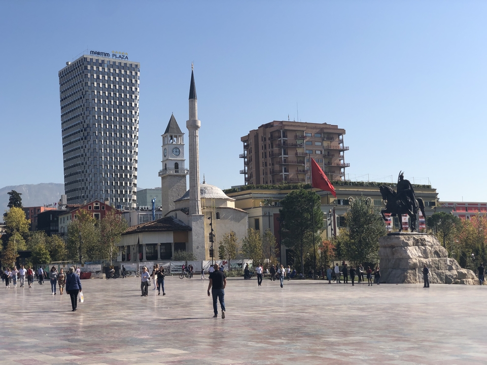 Place de ville animée avec plusieurs monuments et des gens.