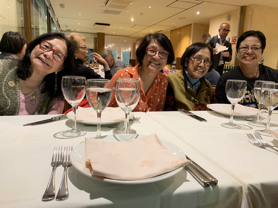 Groupe de personnes assises à une table à manger avec des assiettes et des verres vides.