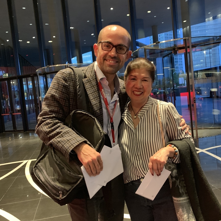 Deux personnes posant à l'intérieur d'un bâtiment avec une entrée vitrée.