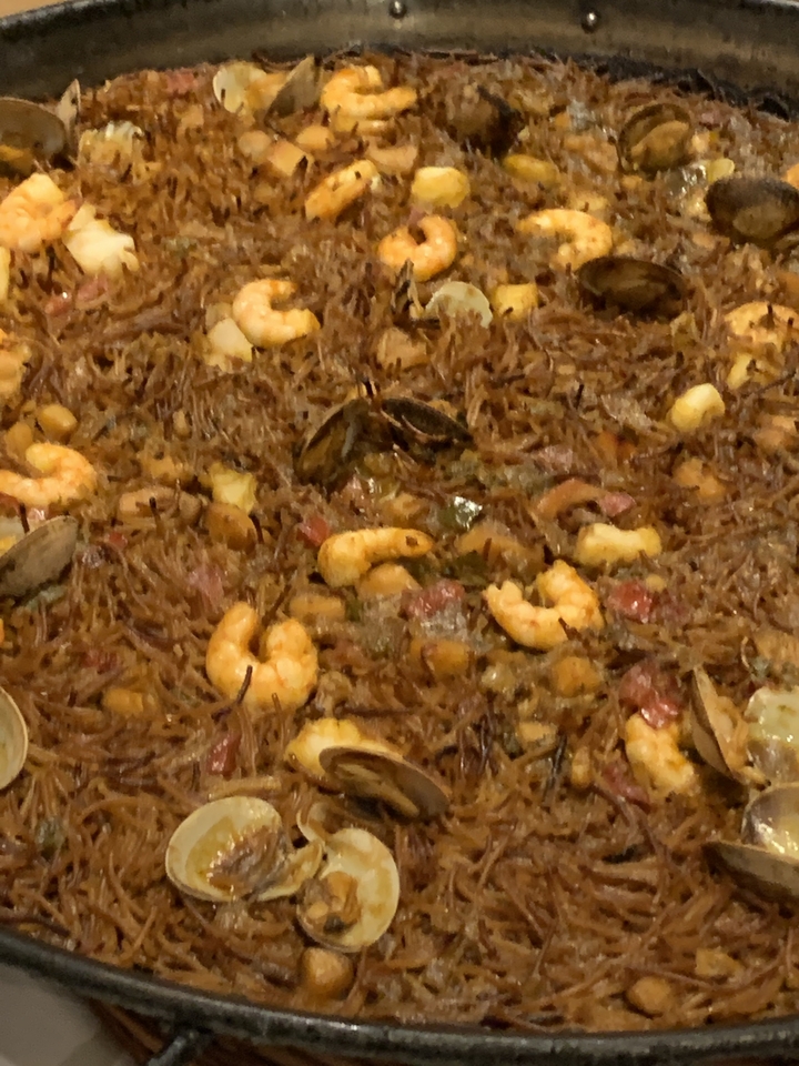 Poêle remplie d'un plat de fruits de mer, incluant des crevettes.