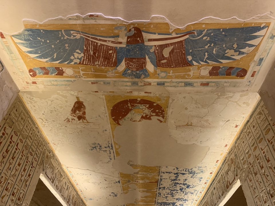 Vue intérieure d'un temple égyptien antique avec des sculptures et un plafond peint.