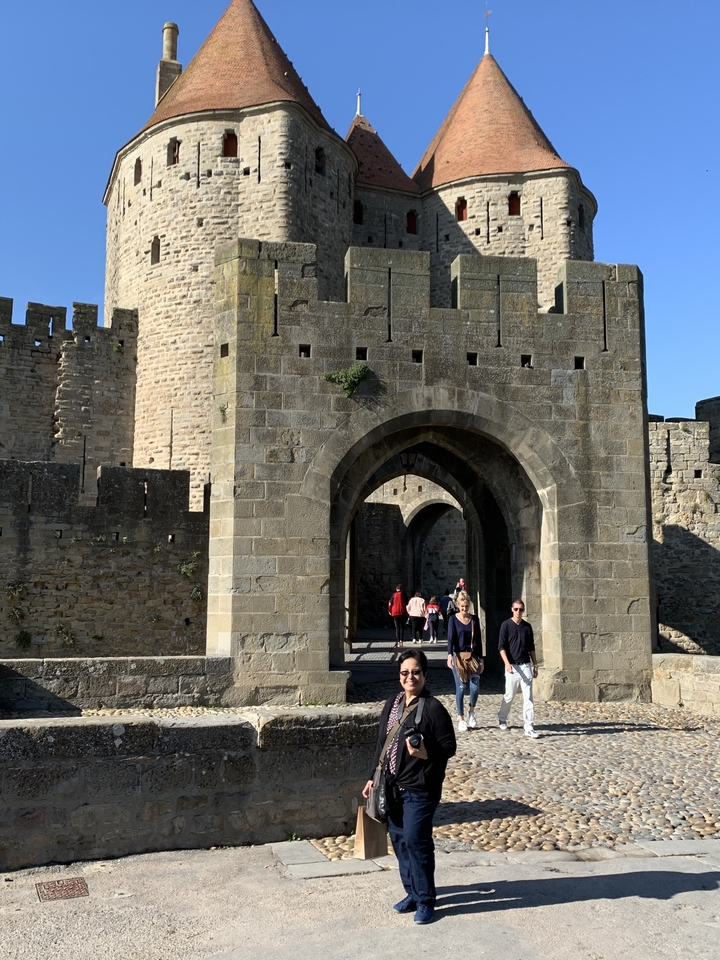 Des gens qui marchent à travers une arche de pierre d'une forteresse.