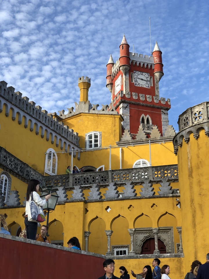Palais coloré avec des gens sur un balcon sous un ciel bleu.