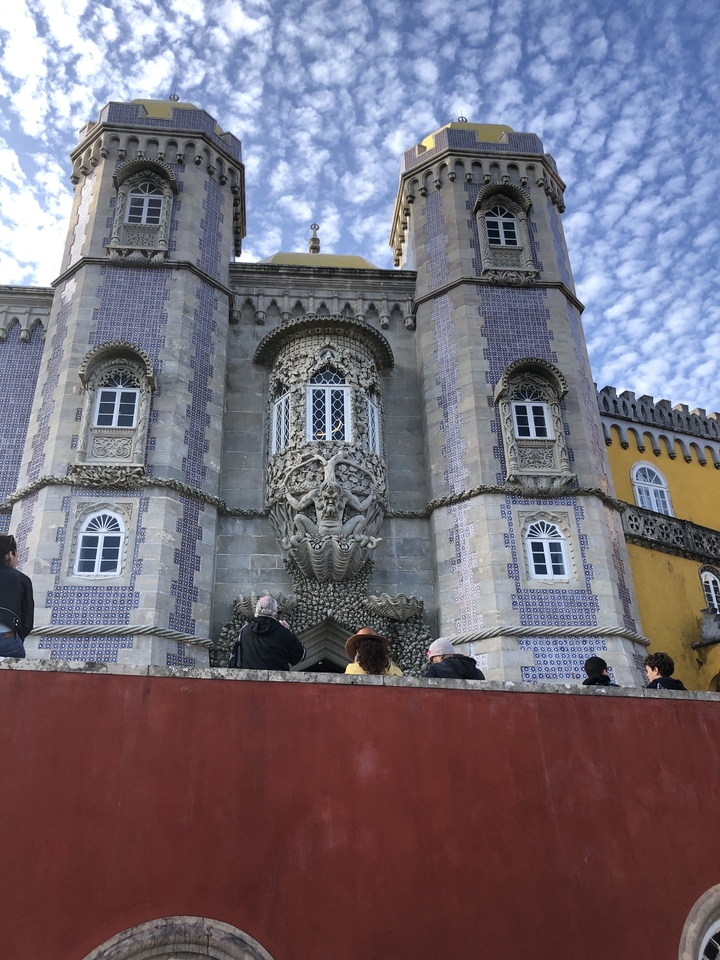 Façade ornée d'un palais avec des gens admirant l'architecture.