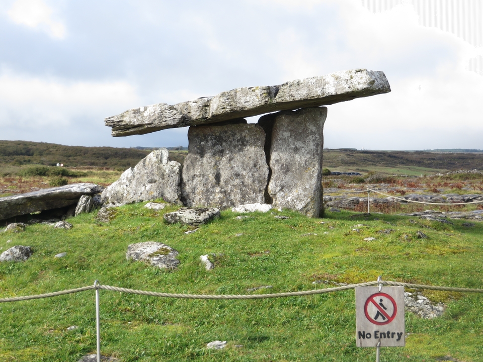 Ancient stone dolmen structure on a grassy field.