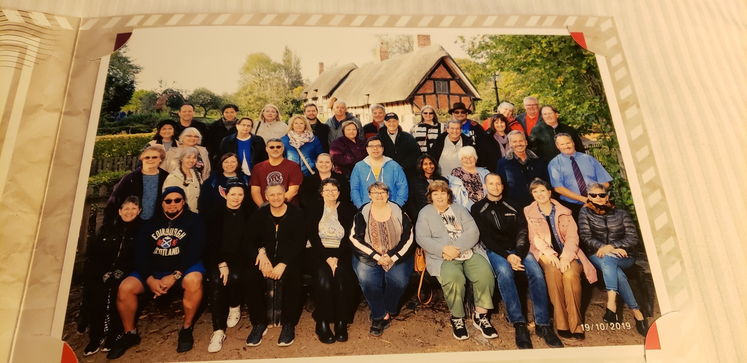 Retrato grupal de turistas frente a una casa en una foto impresa.