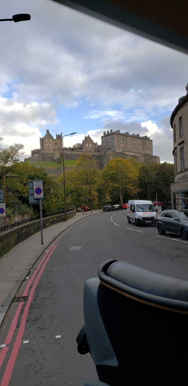 Un castillo visto desde una carretera con árboles de otoño.
