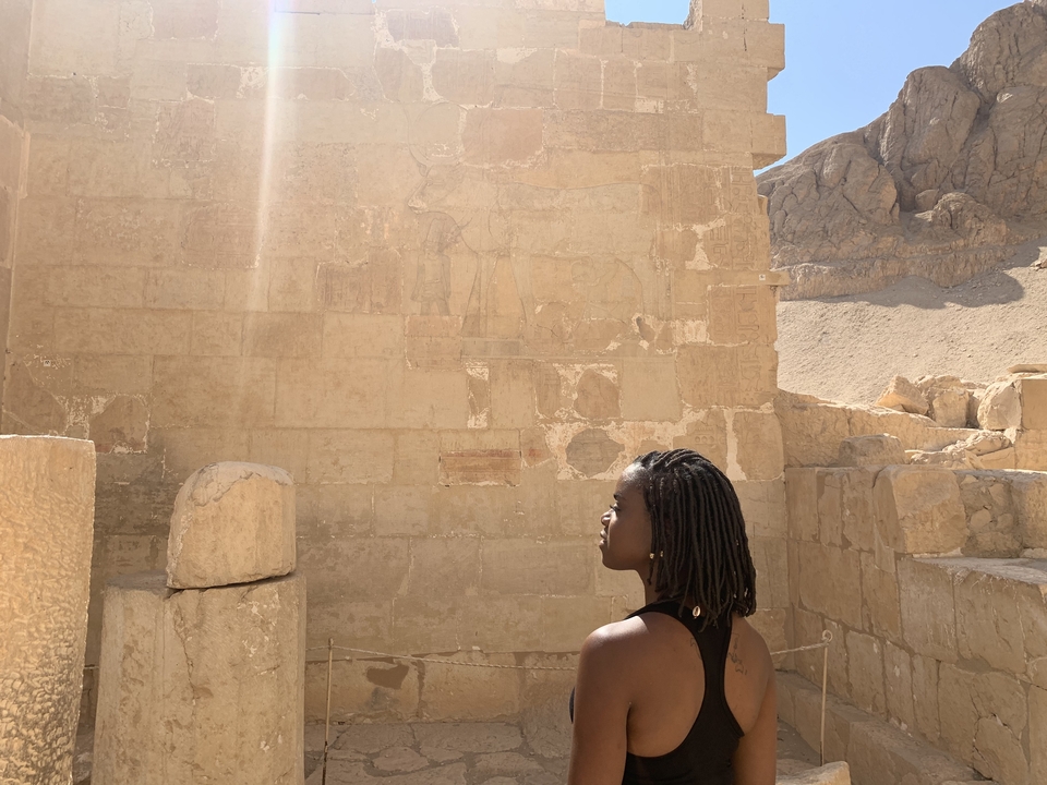 Une femme regardant des hiéroglyphes sur d'anciens murs de pierre.