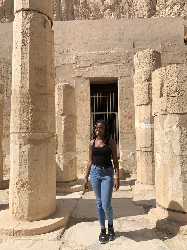 Une femme debout devant des piliers de l'Égypte antique.