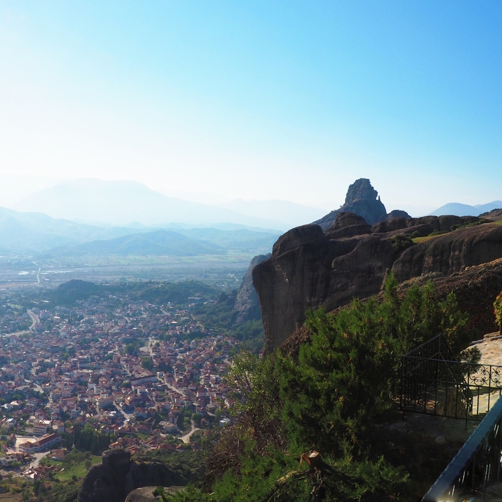 Formations rocheuses spectaculaires avec une vue sur une ville et des collines au loin.