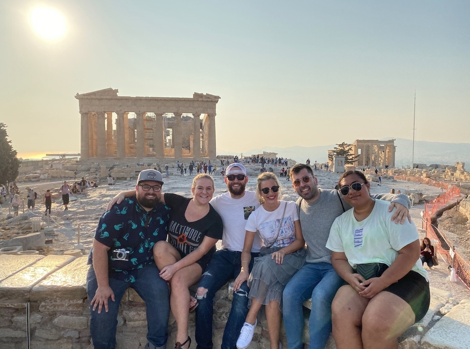Un groupe de personnes posant à l'Acropole avec le Parthénon derrière eux.
