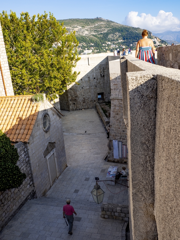 Une ruelle étroite en pierre avec des ombres et une activité minimale.