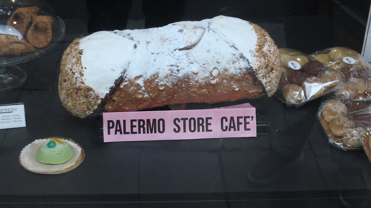 Un étalage avec un grand cannoli et des pâtisseries.
