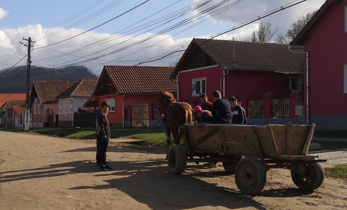 Des gens avec une charrette à cheval dans une rue rurale.