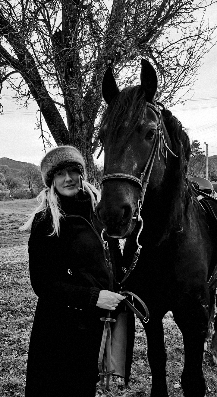 Une femme posant avec un cheval dans un cadre naturel.