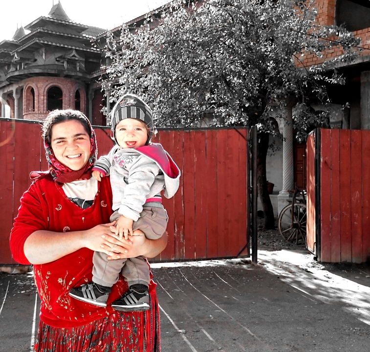 Une femme avec un bébé dans un cadre rural avec un portail rouge.