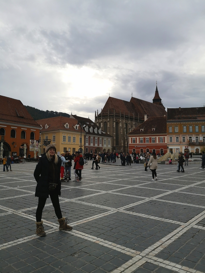 Une femme avec un chapeau se tenant debout sur une place animée avec des bâtiments historiques.